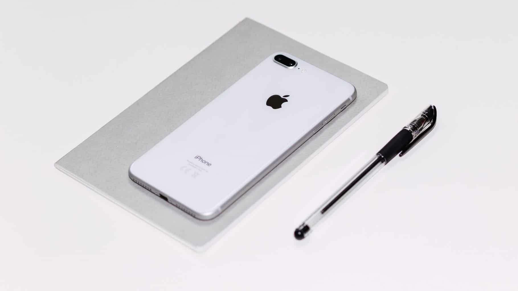 an iPhone, a pen, and a notebook