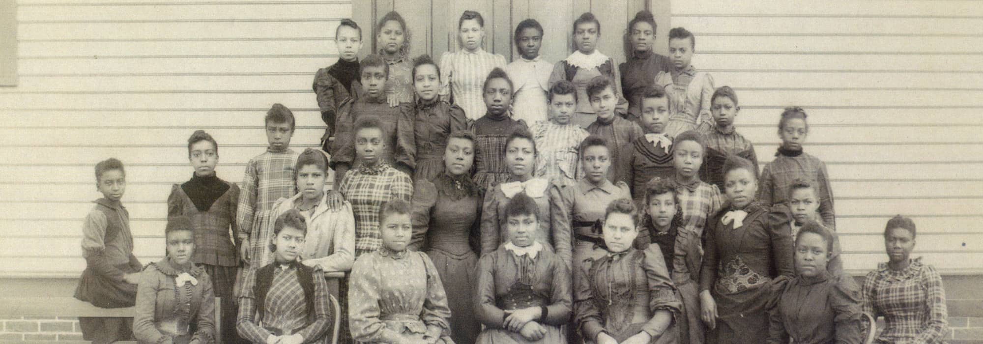 an old photo of students in front of their schoolhouse