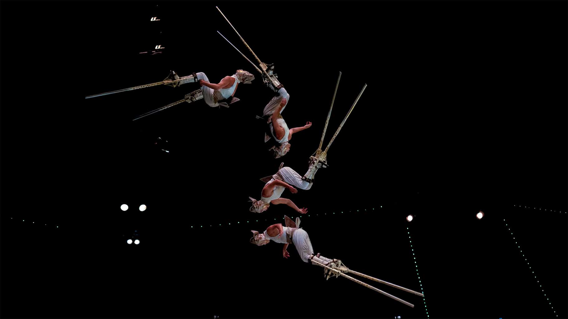 an acrobat on stilts flipping through the air