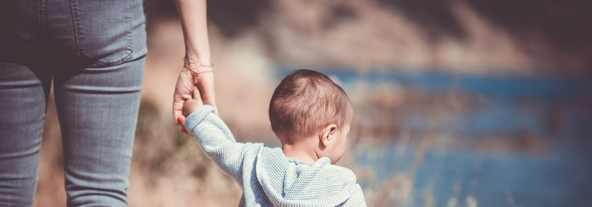mother holding a child's hand on the beach