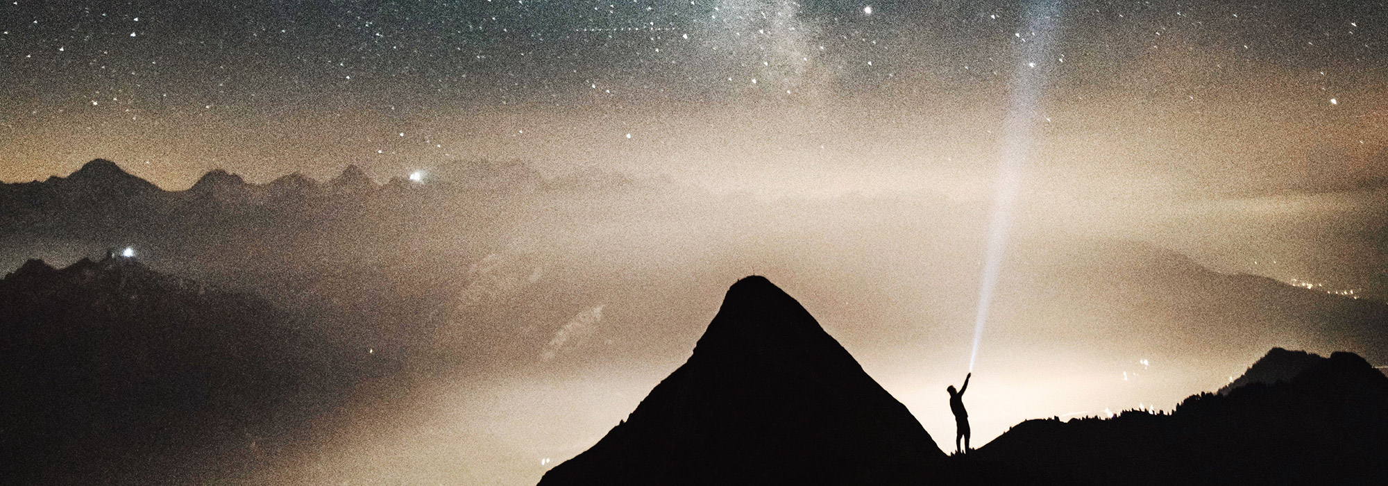 a person holding a flashlight to the night sky
