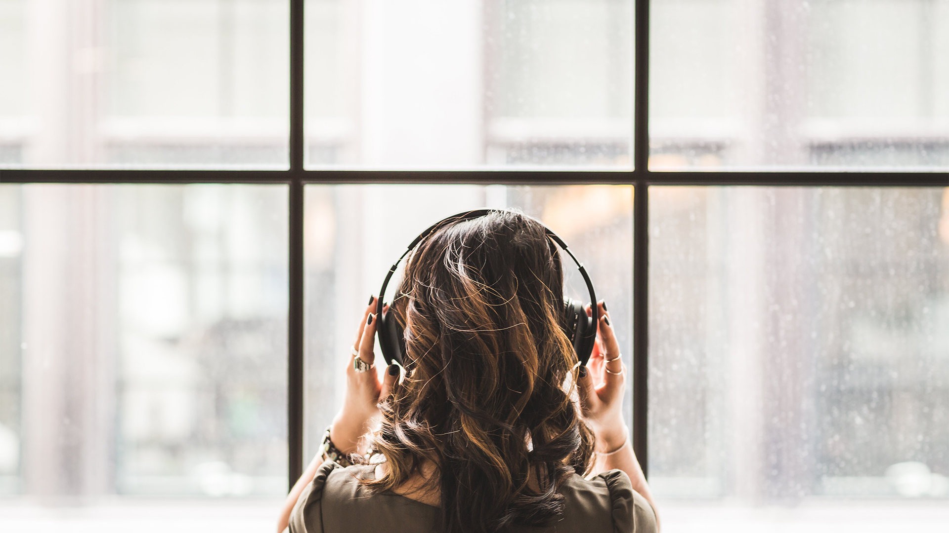 woman with headphones on in front of a large window