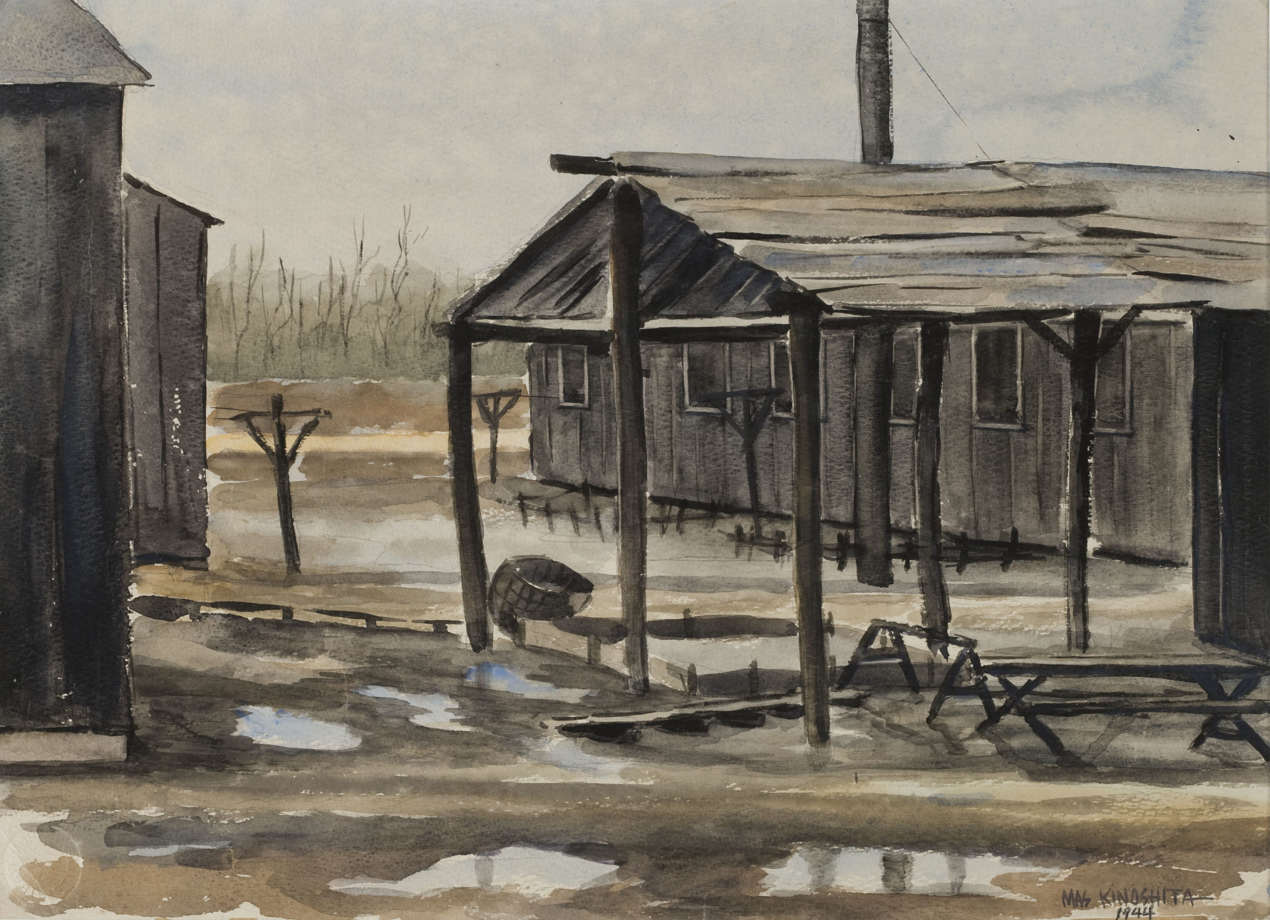 Wooden structures with mud and mud puddles in the foreground.