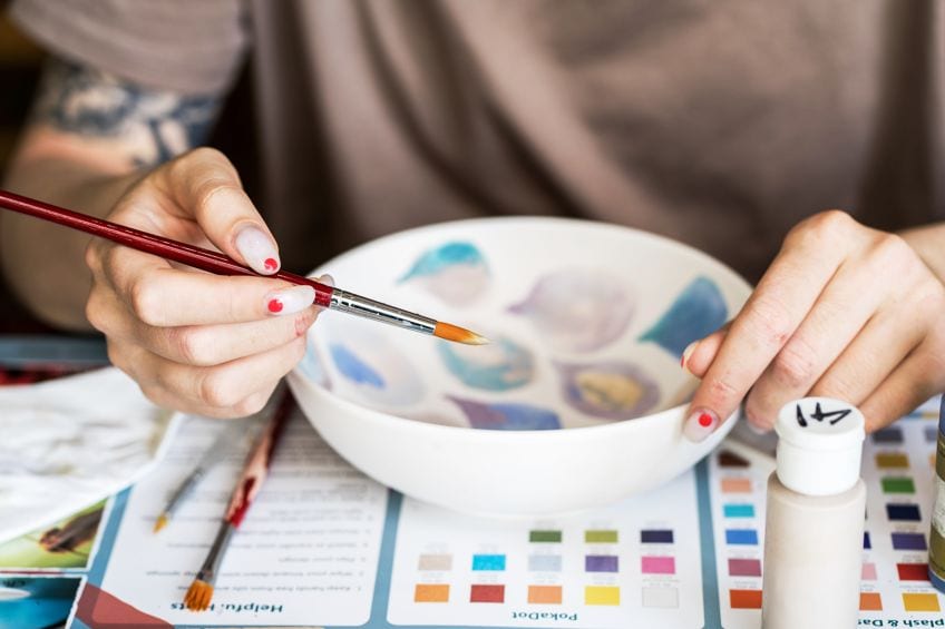 person painting ceramic bowl