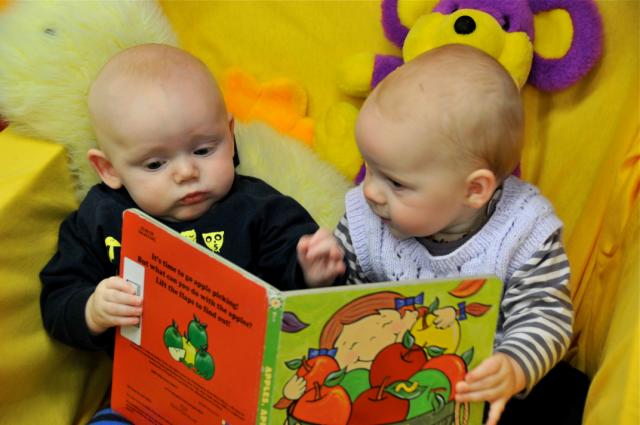 two babies looking at a book together